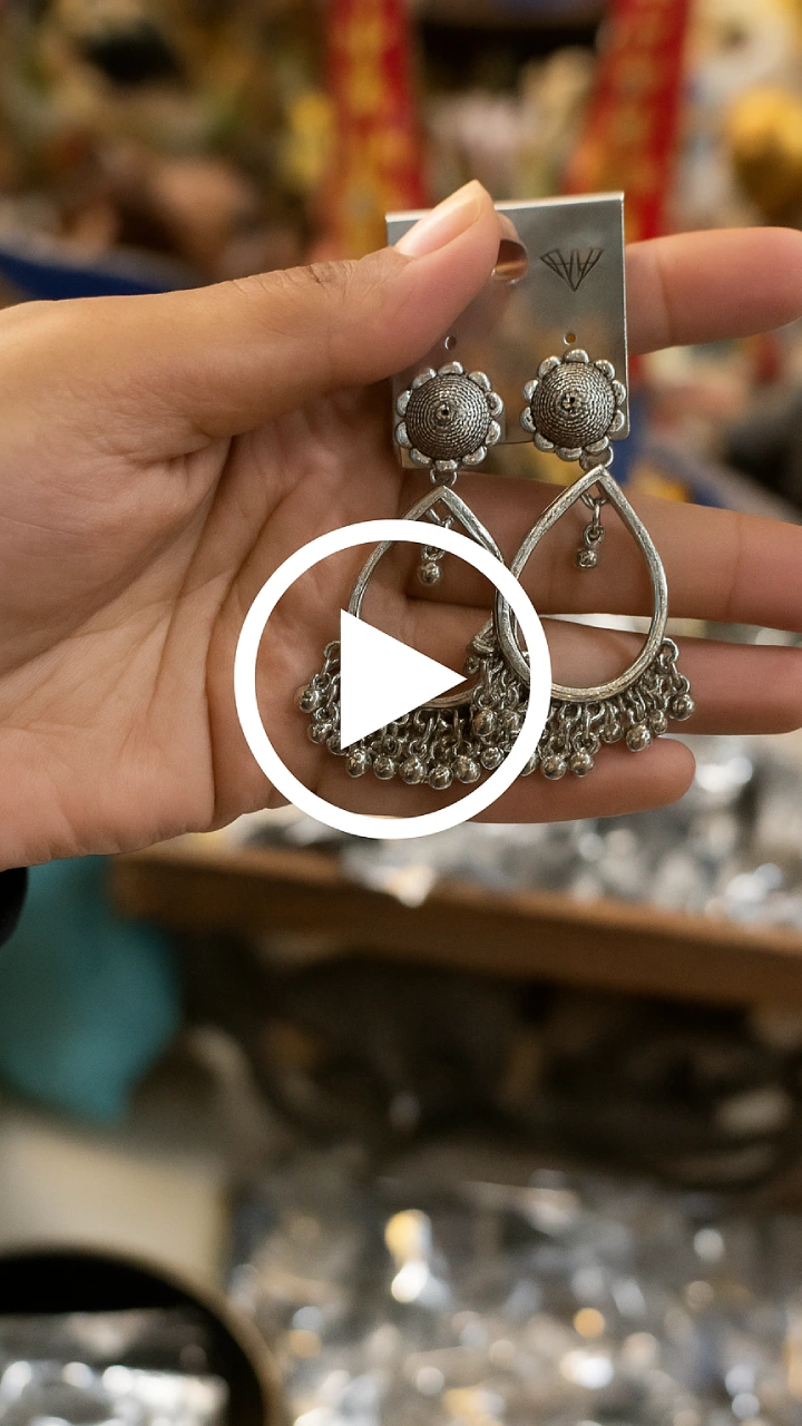 Hand holding oxidised Indian earrings – traditional ethnic jewelry with intricate silver detailing